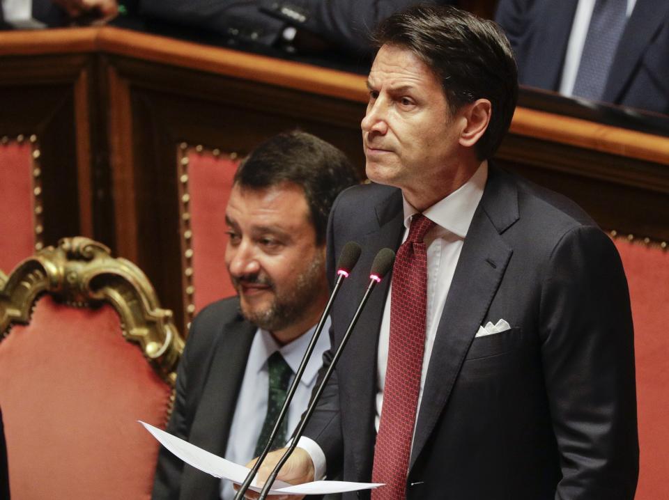 FILE - In this Tuesday, Aug. 20, 2019 file photo, Italian Premier Giuseppe Conte, right, is flanked by Deputy-Premier Matteo Salvini as he addresses the Senate in Rome. When Giuseppe Conte exited the premier’s office, palace employees warmly applauded in him appreciation. But that’s hardly likely to be Conte’s last hurrah in politics. Just a few hours after the handover-ceremony to transfer power to Mario Draghi, the former European Central Bank chief now tasked with leading Italy in the pandemic, Conte dashed off a thank-you note to citizens that sounded more like an ’’arrivederci″ (see you again) then a retreat from the political world he was unexpectedly propelled into in 2018.(AP Photo/Gregorio Borgia, File)