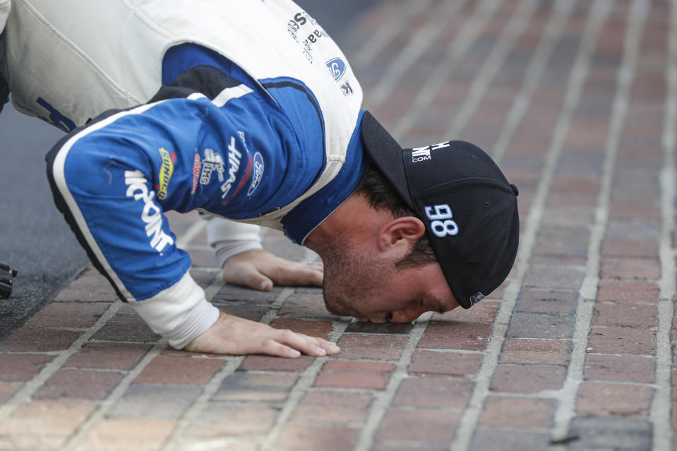 FILE - In this Saturday, July 4, 2020, file photo, NASCAR Xfinity Series driver Chase Briscoe kisses the yard of bricks on the start/finish line after winning the NASCAR Xfinity Series auto race at Indianapolis Motor Speedway in Indianapolis. Briscoe is very clear about his goal of earning a promotion to NASCAR's top Cup Series. He's made his case this season with an Xfinity Series-leading five victories with an eye on adding another win Saturday on the road course at Road America. (AP Photo/Darron Cummings, File)