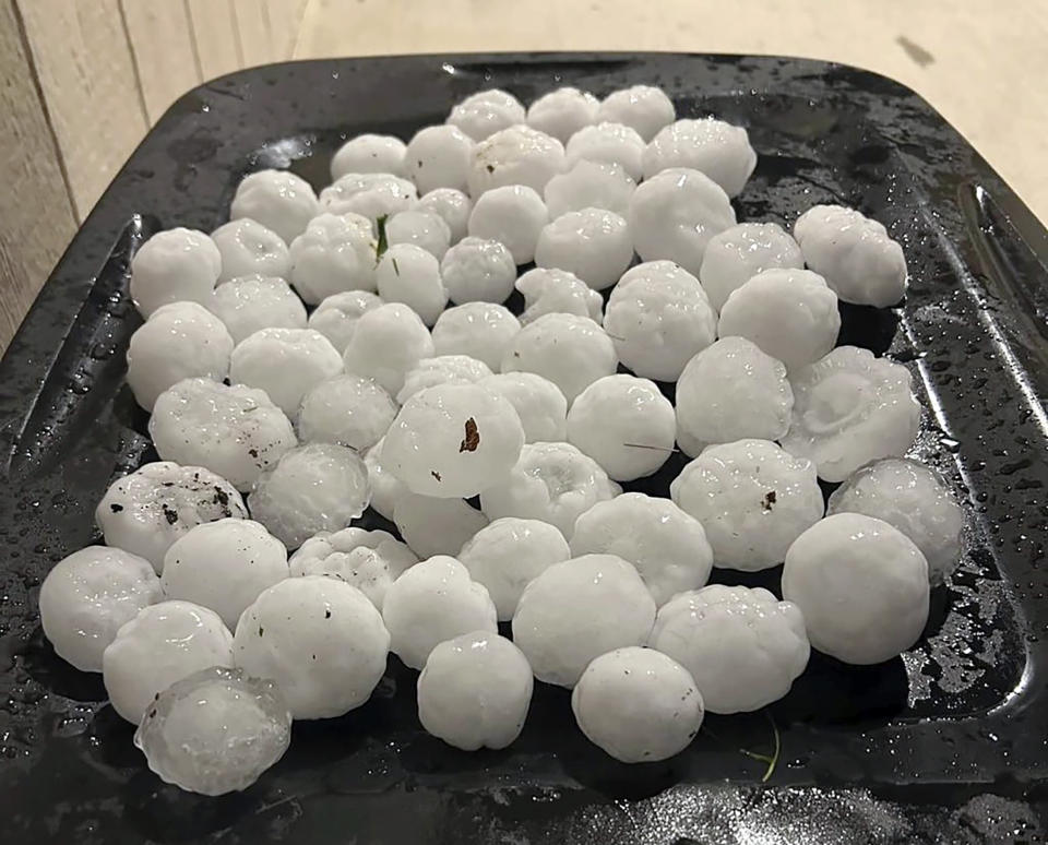 In this image provided by Jeremy Crabtree, large chunks of hail are shown, Wednesday night, March 13, 2024, in Shawnee, Kan. Volatile weather was honing in on parts of Kansas and Missouri Wednesday night, with some storms bringing massive chunks of hail. (Jeremy Crabtree via AP)