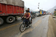 Residents ride a bike as vehicles are parked on the Central Highway after a mudslide in Huarochiri, Lima, Peru, March 23, 2017. REUTERS/Guadalupe Pardo