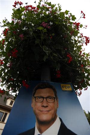 An election campaign poster of German Foreign Minister Guido Westerwelle from the liberal Free Democratic Party (FDP) is placed under a flower pot in the western German town of Bad Honnef near Bonn September 19, 2013. REUTERS/Wolfgang Rattay