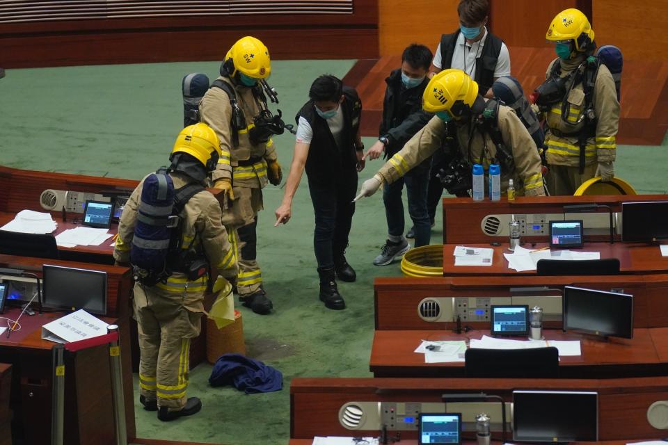 Firefighter and police inspect the main chamber of the Legislative Council after a pro-democracy lawmaker dropping a pot of a pungent liquid in Hong Kong, Thursday, June 4, 2020. A Hong Kong legislative debate was suspended Thursday afternoon ahead of an expected vote on a contentious national anthem bill after pro-democracy lawmakers staged a protest. (AP Photo/Vincent Yu)