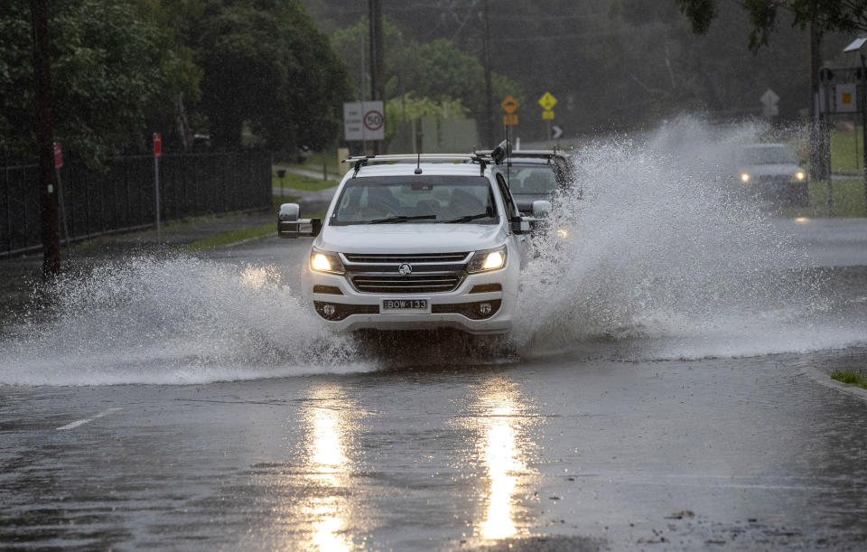 Vehicles plow through water on a flooded road at Port Stephens, 200 kilometers (120 miles) north of Sydney, Australia, Sunday, March 21, 2021. Residents across the state of New South Wales have been warned to prepare for possible evacuations, as NSW Premier Gladys Berejiklian said the state's flood crisis would continue for several more days. (AP Photo/Mark Baker)