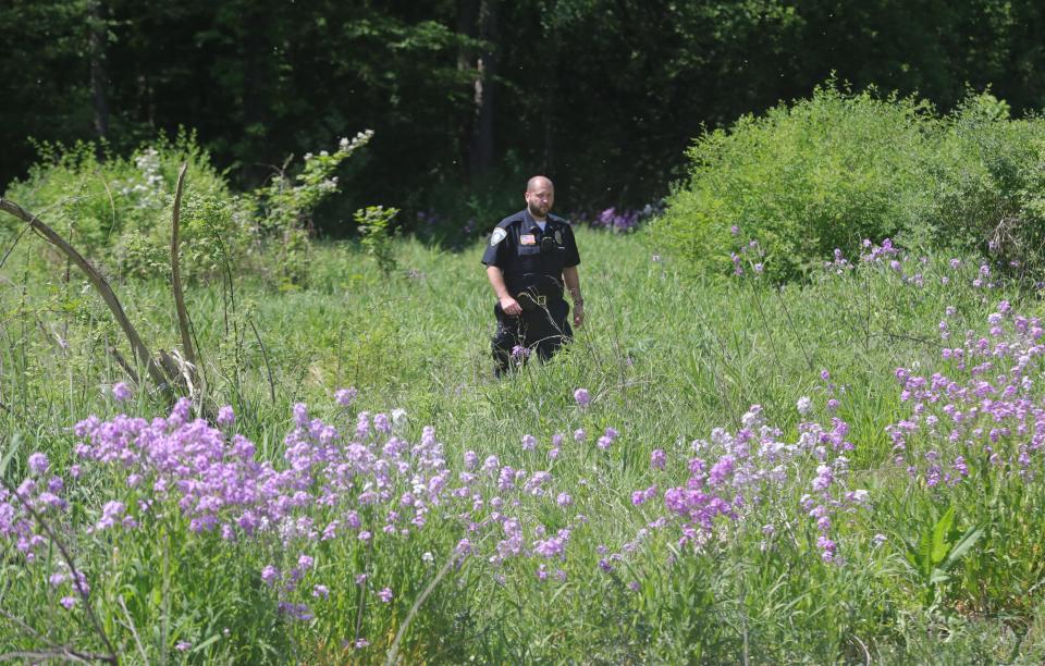 An Akron Children's Hospital police officer searches for escaped prisoner Jason Lyle Conrad in an area off Frank Boulevard near the I-77 overpass on Tuesday, May 30, 2023, in Akron, Ohio.