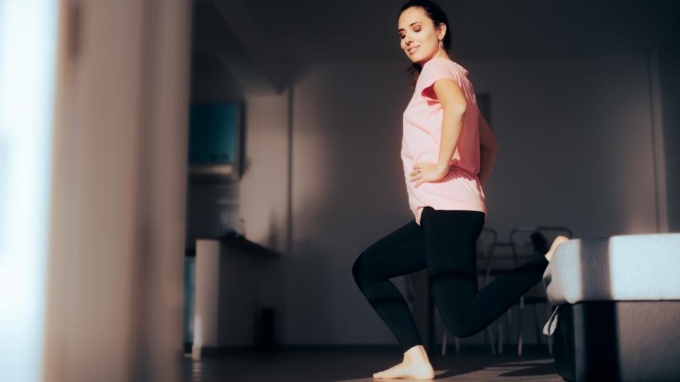 A woman at home doing split squats.