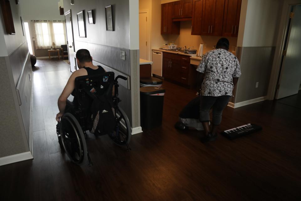 A resident and employee at a group home in New Jersey. Home providers say they hope remote monitoring technology can help them cope with severe staffing shortages.