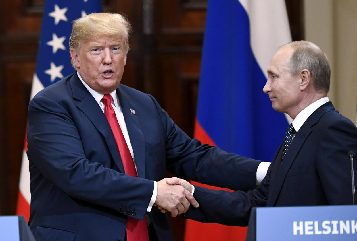 President Trump clasps the hand of an acquiescent President Vladimir Putin with his right hand, while reaching out to pat Putin's arm with his free hand at the same time.
