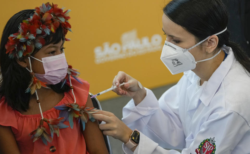 A health worker gives a shot of the Pfizer COVID-19 vaccine to 9-year-old Indigenous youth Stella Para Poty Fernandes Martins at the Hospital da Clinicas in Sao Paulo, Brazil, Friday, Jan. 14, 2022. The state of Sao Paulo started the COVID-19 vaccination of children between ages 5 and 11. (AP Photo/Andre Penner)