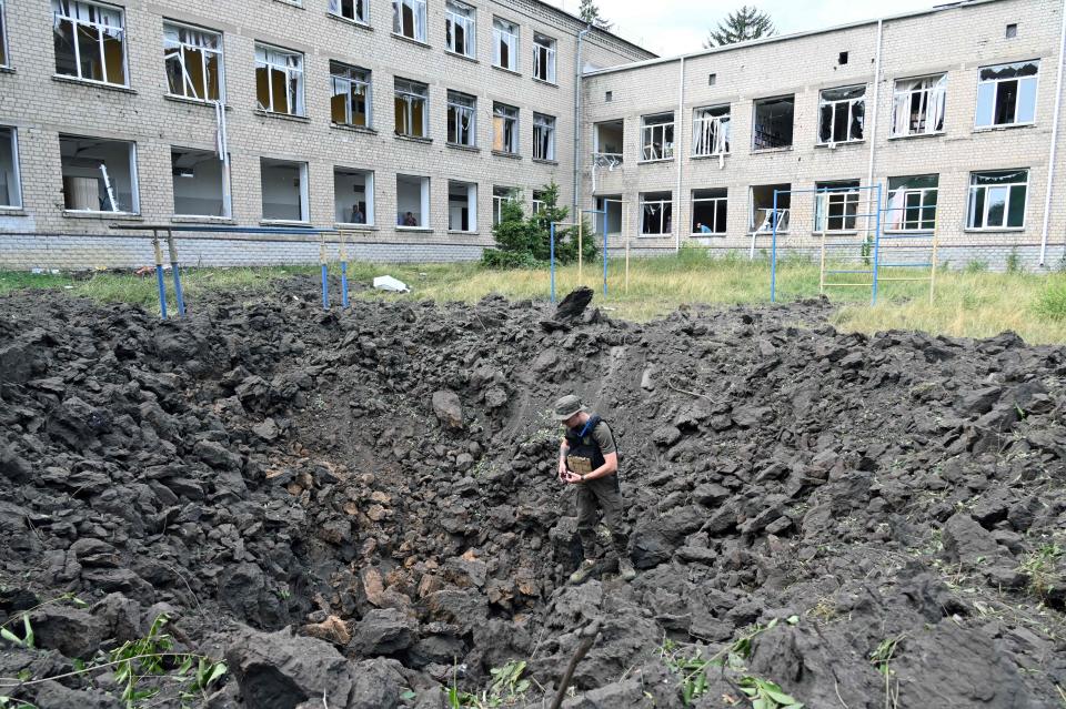 A Ukrainian serviceman examines a crater outside a special comprehensive boarding school for visually impaired children after a strike on its premises, in Kharkiv, on July 7, 2022. The school, before today's hit, had already been shelled twice, on March 16 and July 1.