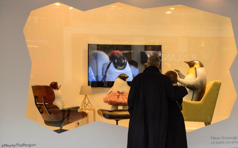 Shoppers on Oxford Street, London, stop to watch the "Monty the Penguin" advert in the window display at the John Lewis department store on November 24, 2014