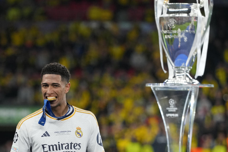 Real Madrid's Jude Bellingham bites his medal walking by the trophy after winning the Champions League final soccer match between Borussia Dortmund and Real Madrid at Wembley stadium in London, Saturday, June 1, 2024. (AP Photo/Kirsty Wigglesworth)