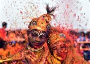 <p>Tribal Indian students from the Kalinga Institute of Social Science (KISS), dressed as Lord Krishna and Radha, are smeared with with coloured powder and petals during Holi festival celebrations in Bhubaneswar on March 1, 2018.<br> (Photo: Asit Kumar/AFP/Getty Images) </p>