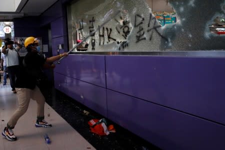 An anti-extradition bill protester smashes Mass Transit Railway (MTR) facility as they accuse the railway operator of helping the government to catch protesters, at Tung Chung, in Hong Kong