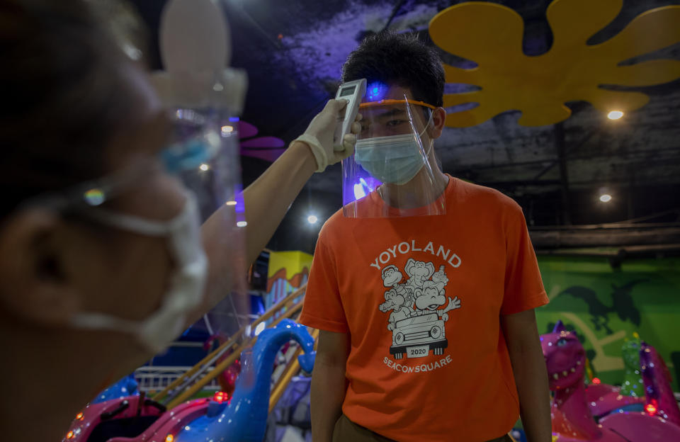 An employee measures the temperature of another in Yoyo Land, an indoor amusement center in Bangkok, Thailand, Tuesday, June 16, 2020. Daily life in the capital resumes to normal as the government continues to ease restrictions related to running business and activities that were imposed weeks ago to combat the spread of COVID-19. Thailand reported no local transmissions of the coronavirus in the past 3 weeks. (AP Photo/ Gemunu Amarasinghe)