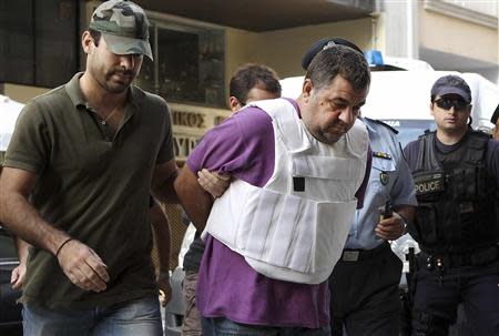 Police officers escort a man (C), a supporter of the far-right Golden Dawn group and who admitted to the fatal stabbing of anti-racism rapper Pavlos Fissas, into a prosecutor's office in Piraeus, near Athens September 21, 2013. REUTERS/John Kolesidis