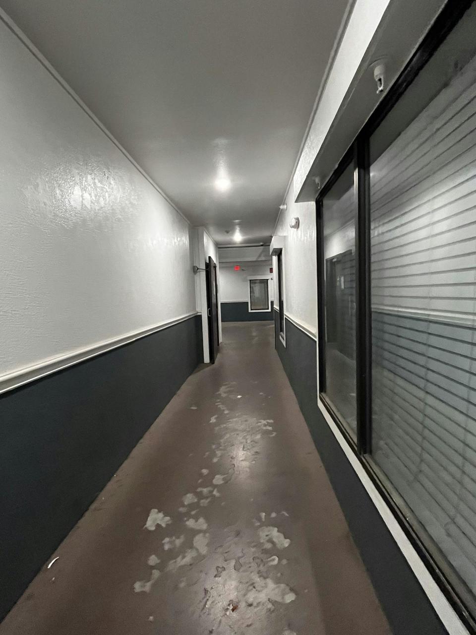 A hallway with paint-scuffed floors illuminated by light bulbs.