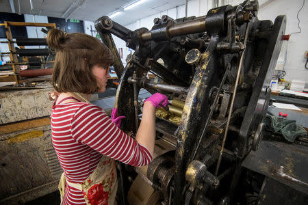 Lottie Small adds gold ink to the die stamping press at the workshop of Barnard and Westwood, who are printing the invitations for Prince Harry and Meghan Markle's wedding at Windsor Castle in May, London, Britain March 22, 2018. Victoria Jones/Pool via Reuters