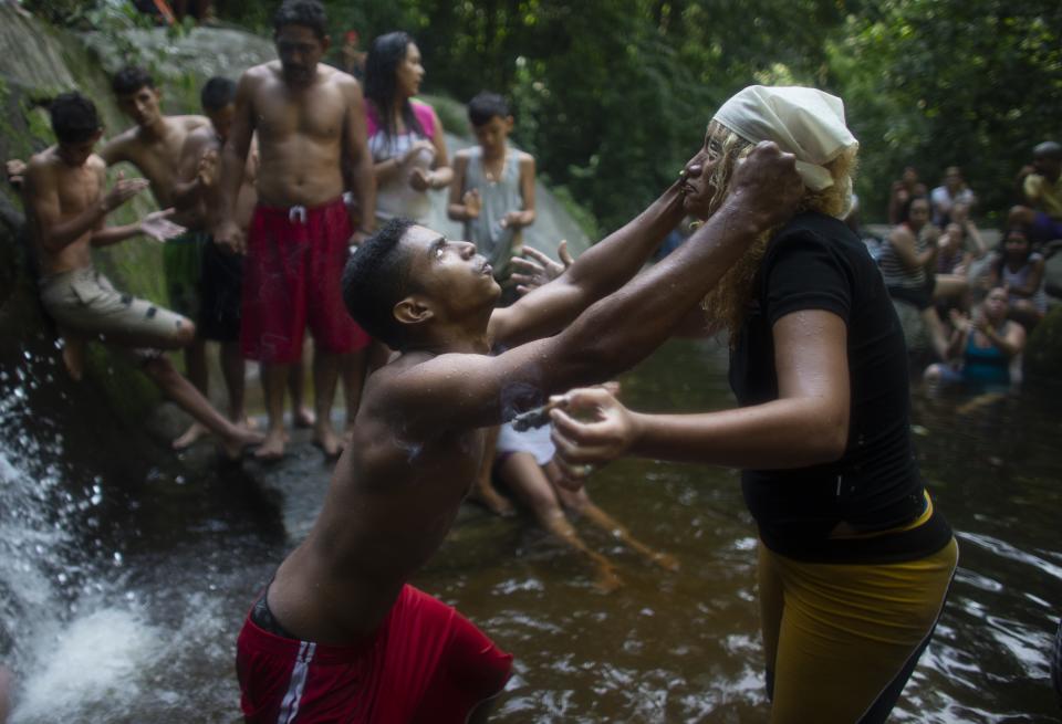 In this photo taken Oct. 12, 2019, a man's eyes roll backwards as he partakes in a ritual with a spiritual healer known as a "madrina" on Sorte Mountain where followers of indigenous goddess Maria Lionza gather annually in Venezuela's Yaracuy state. Venezuela is predominantly Roman Catholic, and while the church disapproves of the folk religion, it has long since abandoned its attempts to suppress it. (AP Photo/Ariana Cubillos)