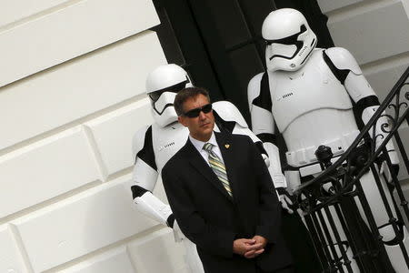 Two costumed Stormtroopers, from the Star Wars movie series, stand with a Secret Service agent at the annual Easter Egg Roll at the White House in Washington March 28, 2016. REUTERS/Jonathan Ernst