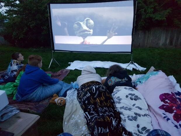 The Plunkett siblings are pictured watching a movie in their backyard during the pandemic. 