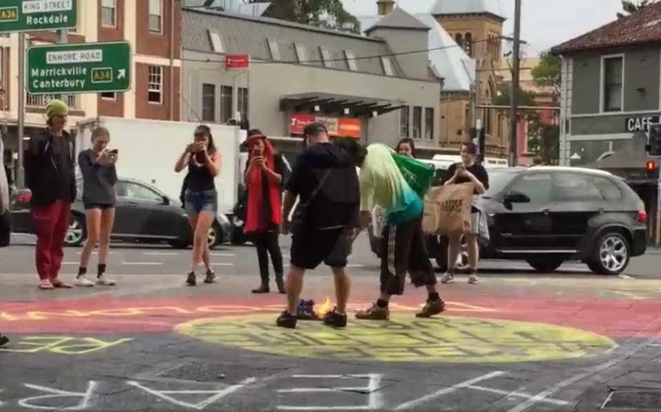 Protesters in Newtown set a flag on fire in the middle of a public thoroughfare.