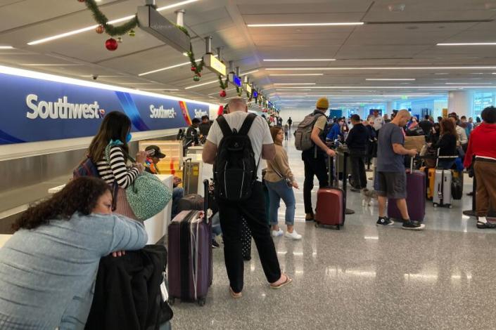 Travelers wait to pick up their bags at a Southwest Airlines baggage counter after a flight is canceled at Los Angeles International Airport in Los Angeles, Monday, Dec. 26, 2022.  (AP Photo/Eugene Garcia)