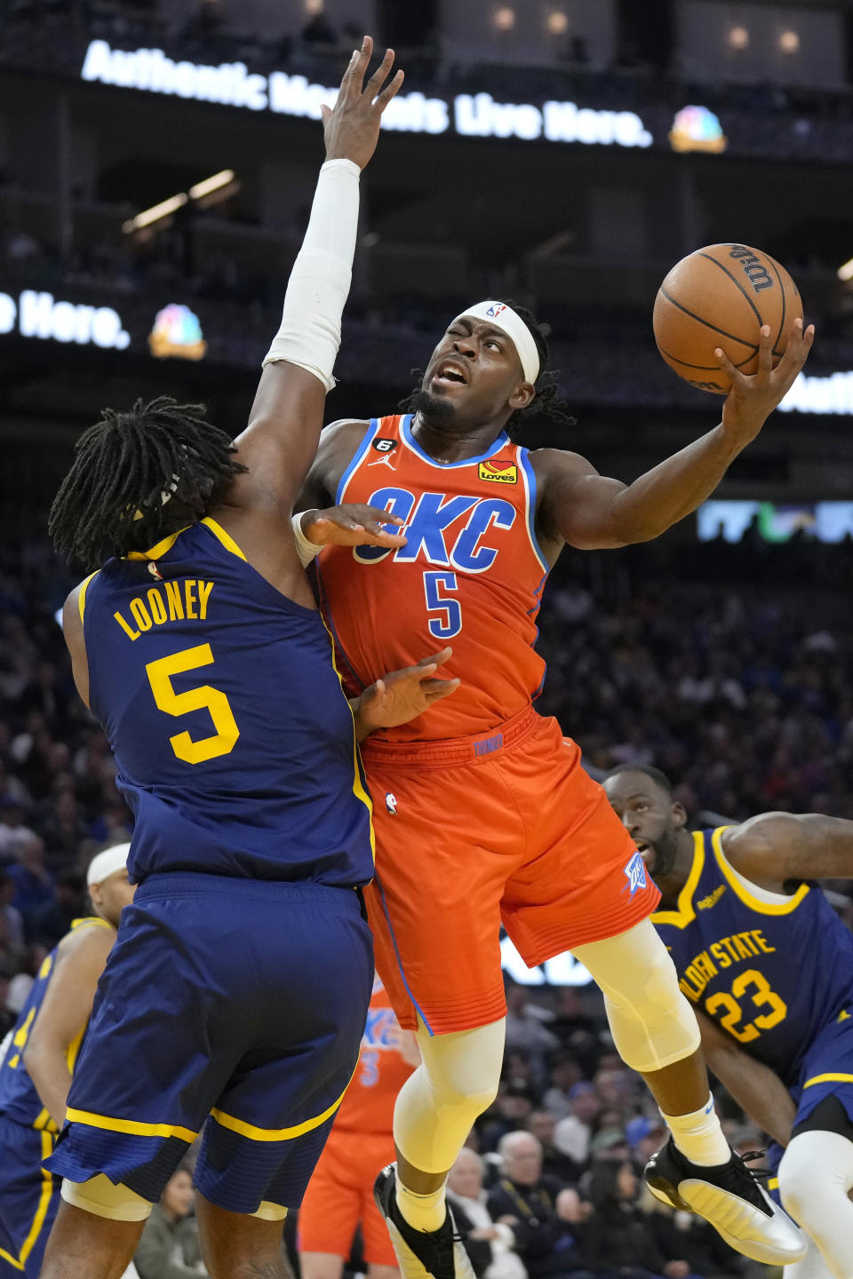 Oklahoma City Thunder guard Luguentz Dort, right, shoots against Golden State Warriors forward Kevon Looney during the first half of an NBA basketball game in San Francisco, Tuesday, April 4, 2023. (AP Photo/Jeff Chiu)