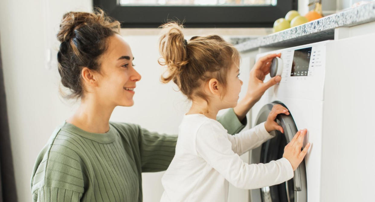 Mother and child with washing machine (Getty Images)