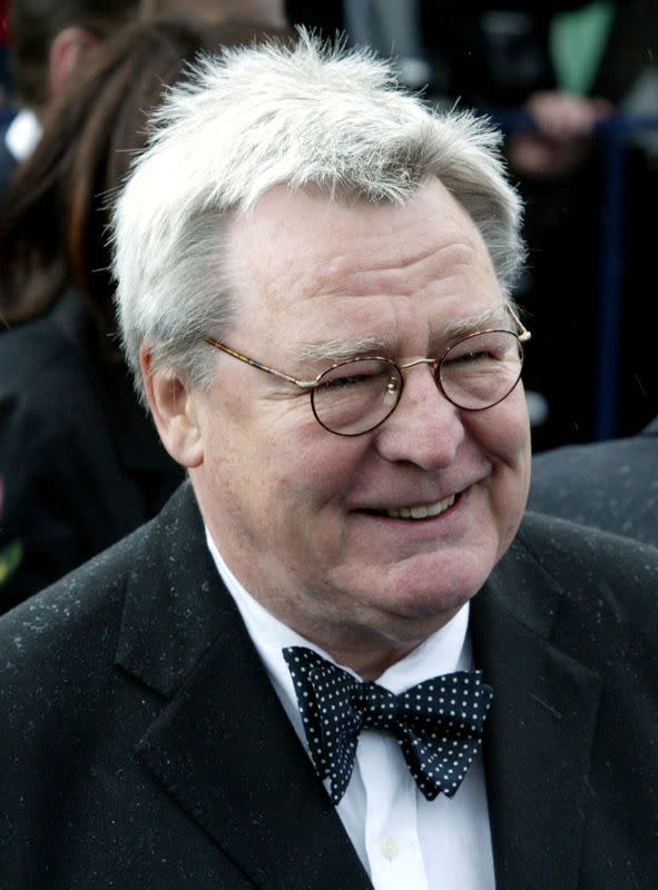 FILE PHOTO: British Director Alan Parker walks through the rain as he attends the opening ceremony of the 26th M..