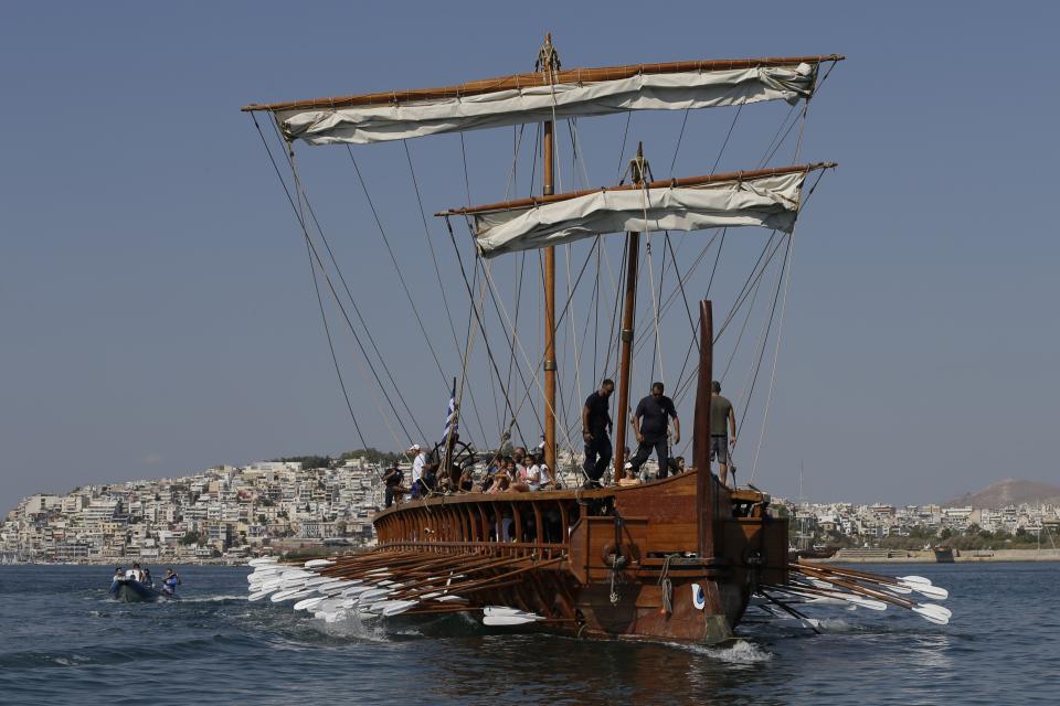 In this Sunday, Sept. 16, 2018 photo, visitors row the Olympias, a replica of an ancient galley, at Saronic gulf in southern Athens. The 37-meter (121-foot) wooden vessel moored off southern Athens is an experimental reconstruction of the trireme, the sleek ancient Greek warship that halted a Persian invasion of Europe and ruled the Mediterranean for centuries. Every summer, visitors can get a whiff of life in the galleys 2,500 years ago by joining the crew of the Olympias, and work up a sweat rowing it. (AP Photo/Thanassis Stavrakis)