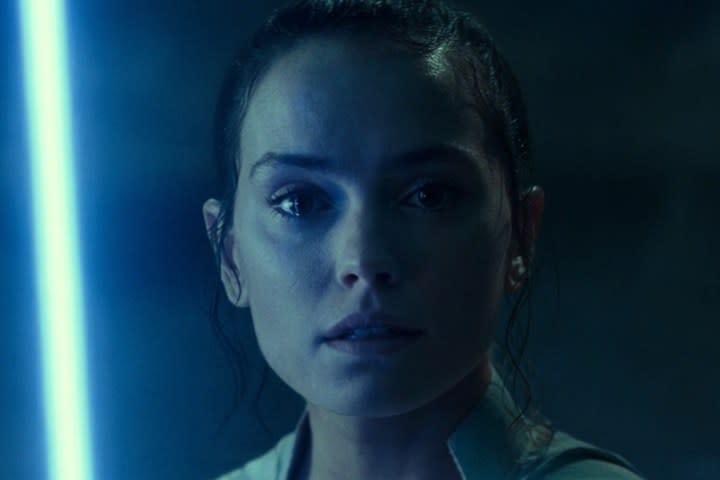 A blue lightsaber lights up Rey's face in Star Wars: Episode IX - The Rise of Skywalker.