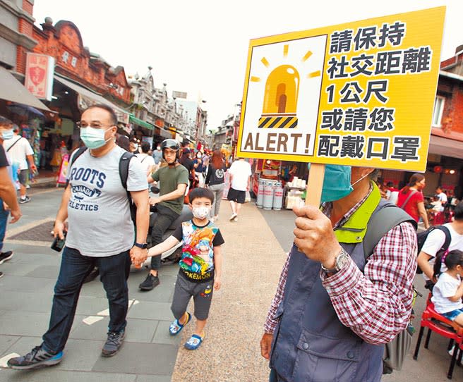 桃園大溪老街有志工在入口處舉牌宣導，大部分的遊客也都配合政策戴上口罩。（范揚光攝）