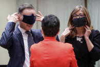 German Foreign Minister Heiko Maas, left, and Bulgaria's Foreign Minister Ekaterina Zharieva, right, put on their face masks, to prevent the spread of coronavirus, as they speak with Spain's Foreign Minister Arancha Gonzalez during an EU foreign ministers at the European Council building in Brussels, Monday, July 13, 2020. European Union foreign ministers meet for the first time face-to-face since the pandemic lockdown and will assess their discuss their relations with China and Turkey. (Stephanie Lecocq, Pool Photo via Ap)