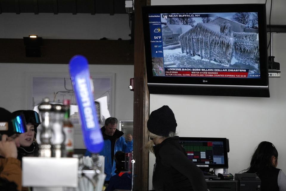 News of climate disasters are displayed on a television overlooking a bar at the Sundeck Restaurant at Aspen Mountain on Tuesday, Jan. 10, 2023, in Aspen, Colo. As global warming threatens to put much of the ski industry out of business over the next several decades, resorts are beginning to embrace a role as climate activists. (AP Photo/Brittany Peterson)