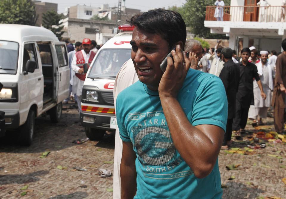 A man uses his mobile phone as he mourns the death of his relatives at the site of a blast at a church in Peshawar