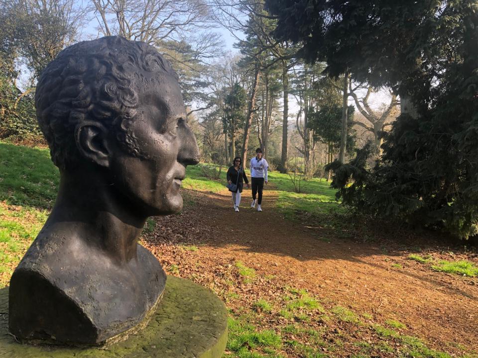A bust of a man's head on a nature walk.