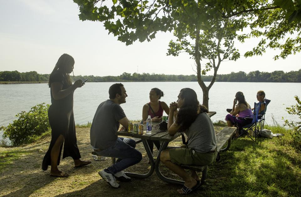 Former college roomates Alex Marson, left, and Cassim Shepard, along with Shepard's wife Heather McGhee, left, and her sister Shannon McGhee visit on a tiny pennisula of land that stretches into the Carbondale Reservoir as they wait for the total solar eclipse Monday, Aug. 21, 2017. Shepard said he's been waiting to view the eclipse since he saw a commercial for the Mitsubishi Eclipse as a nine-year-old that advertised the 2017 event. "I thought the future would be here," Shepard said, who also thought we'd be traveling in solar-powered vehicles to the moon. [Ted Schurter/The State Journal-Register]