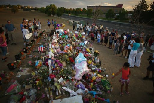 People are seen visiting a memorial setup across the street from the Century 16 movie theatre where James Holmes is suspected of a mass shooting, on July 26, in Aurora, Colorado