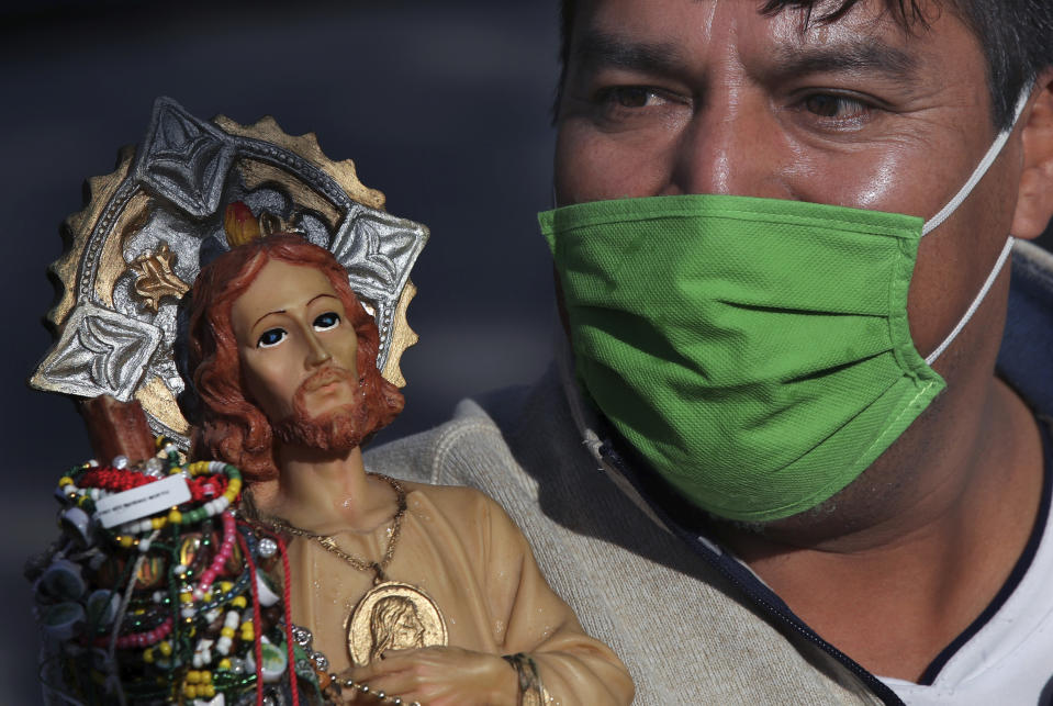 Un devoto con una mascarilla protectora para protegerse del nuevo coronavirus, espera en la fila para ingresar a la iglesia católica San Hipólito como parte de la peregrinación anual en honor a San Judas, el santo patrón de las causas perdidas, en la Ciudad de México, el miércoles 28 de octubre de 2020. (AP Foto/Marco Ugarte)