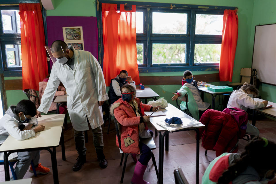 Wearing face masks amid the new coronavirus pandemic, a teacher leads his class on the first day back to a rural school near Empalme Olmos, Uruguay, Monday, June 1, 2020, as Uruguay’s total lockdown begins to ease. (AP Photo/Matilde Campodonico)