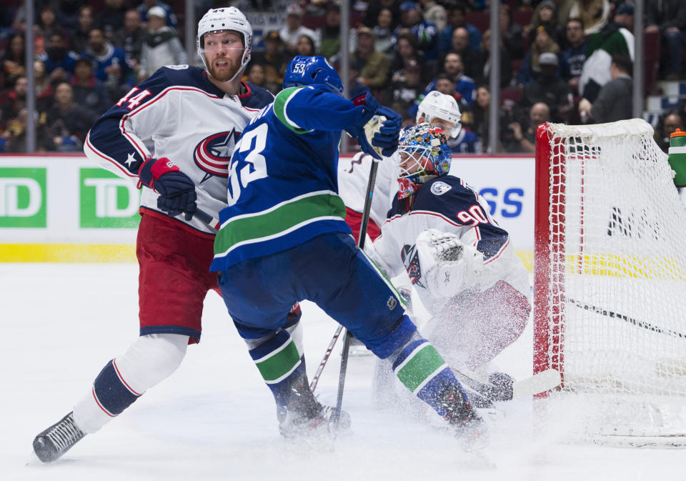 Columbus Blue Jackets defenseman Vladislav Gavrikov (44) tries to block Vancouver Canucks center Bo Horvat (53) from closing in near Columbus Blue Jackets goaltender Elvis Merzlikins (90) during the second period of an NHL hockey game in Vancouver, British Columbia, Sunday, March 8, 2020. (Jonathan Hayward/The Canadian Press via AP)