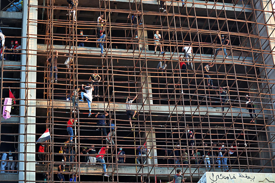 In this Oct. 31, 2019, photo, Iraqi anti-government protesters climb a building near Tahrir Square, Baghdad, Iraq. An abandoned building in central Baghdad has emerged as the epicenter of anti-government protests in Iraq, with hundreds holed up inside. The Saddam Hussein-era building known as the “Turkish Restaurant” overlooks Tahrir Square, the Tigris River and the Green Zone, and protesters who took it over on Oct. 25 have sworn not to leave it. (AP Photo/Khalid Mohammed)