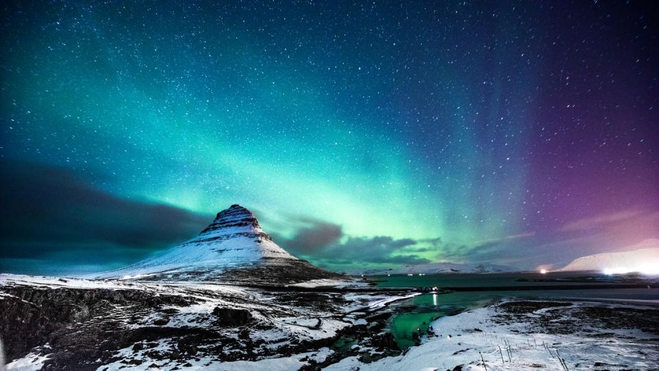 northern lights in mount kirkjufell iceland with a man passing by