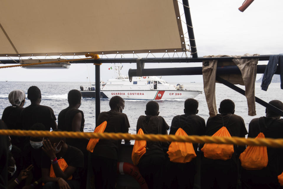 Some of the 353 migrants rescued by Sea-Watch 4 look at an Italian Coast Guard boat as they wait to board the quarantine Ferry Gnv Allegra, in front of the port of Palermo, Italy, Wednesday, Sept. 2, 2020. (Chris Grodotzki/Sea-Watch.org via AP)