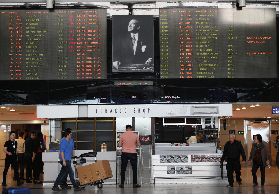 With a poster of Mustafa Kemal Ataturk, modern Turkey's founder, between flight information boards, people walk at Ataturk International Airport, in Istanbul, Friday, April 5, 2019, ahead of its closure. The relocation from Ataturk International Airport to Istanbul Airport on the Black Sea shores— dubbed the "Great Move"—began early Friday and is expected to end Saturday. The Istanbul Airport —one of Turkish President Recep Tayyip Erdogan's mega projects— partially opened in October and will serve 90 million passengers annually. (AP Photo/Lefteris Pitarakis)
