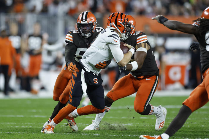 Cincinnati Bengals quarterback Joe Burrow, center, is sacked by Cleveland Browns linebacker Deion Jones, left, during the second half of an NFL football game in Cleveland, Monday, Oct. 31, 2022. (AP Photo/Ron Schwane)