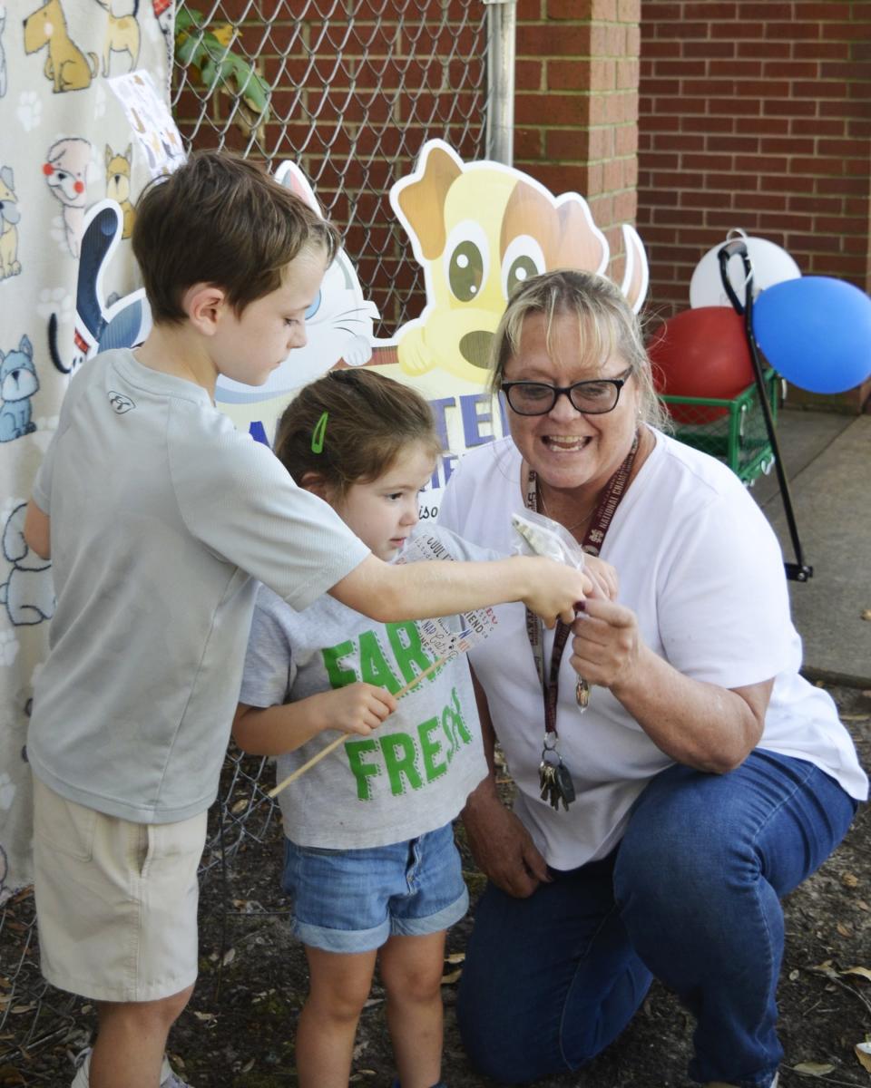 Vicki Currie, from right, an investigator with the Madison Police Department, accepts a donation for the Webster Animal Shelter in Madison from Emerson Weiland, 3, and Charles Weiland, 7, of New Orleans, La., during Night Out festivities in Madison Tuesday, Oct. 3.