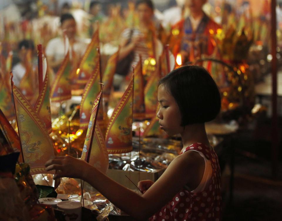 A child decorates food offerings at the Hungry Ghost festival in Kuala Lumpur August 3, 2014. According to Taoist and Buddhist beliefs, the seventh month of the Chinese Lunar calendar, known as the Hungry Ghost Festival is when the Gates of Hell open to let out spirits who wander the land of the living looking for food. Food offerings are made while paper money and joss sticks are burnt to keep the spirits of dead ancestors happy and to bring good luck. REUTERS/Olivia Harris (MALAYSIA - Tags: SOCIETY RELIGION)