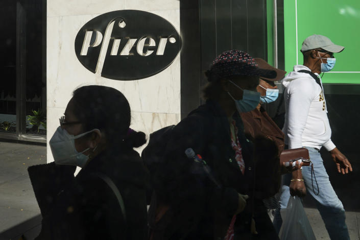 FILE - In this Nov. 9, 2020, file photo, pedestrians walk past Pfizer world headquarters in New York. Pfizer announced Wednesday, Nov. 18, 2020, more results in its ongoing coronavirus vaccine study that suggest the shots are 95% effective a month after the first dose. (AP Photo/Bebeto Matthews, File)