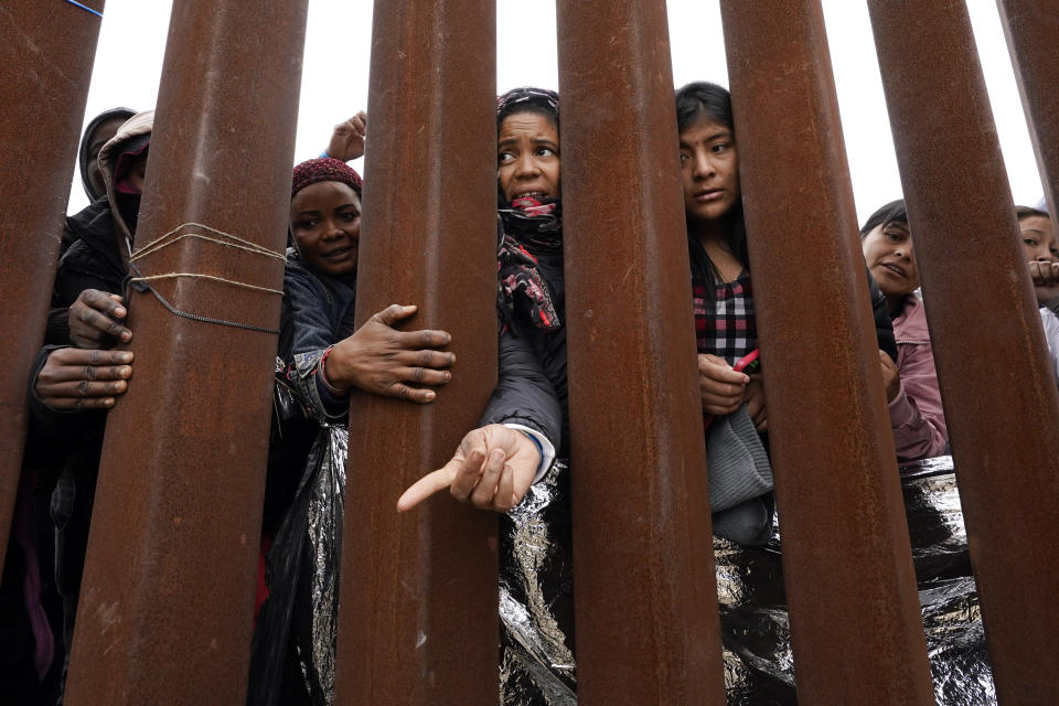 Migrants reach through a border wall for clothing handed out by volunteers, as they wait between two border walls to apply for asylum Friday, May 12, 2023, in San Diego. Hundreds of migrants remain waiting between the two walls, many for days. The U.S. entered a new immigration enforcement era Friday, ending a three-year-old asylum restriction and enacting a set of strict new rules that the Biden administration hopes will stabilize the U.S.-Mexico border and push migrants to apply for protections where they are, skipping the dangerous journey north. (AP Photo/Gregory Bull)